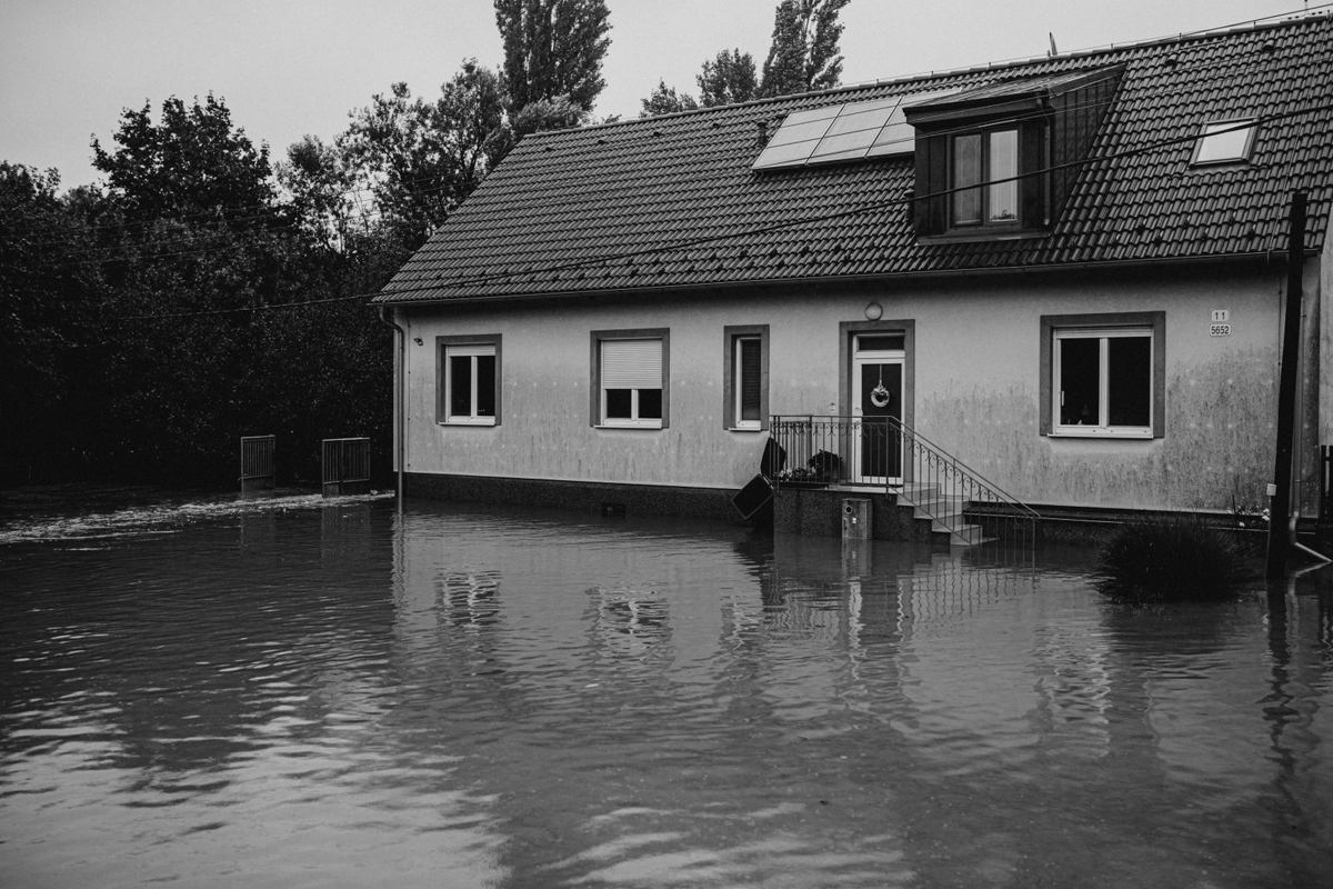 Single-family house with floodwater standing across the yard up to the front steps after a storm